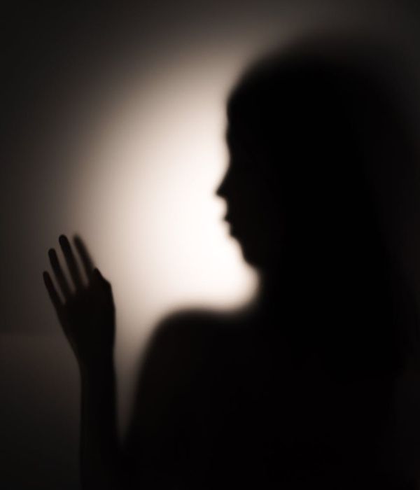 Silhouette of a woman stretching against a soft, abstract background.